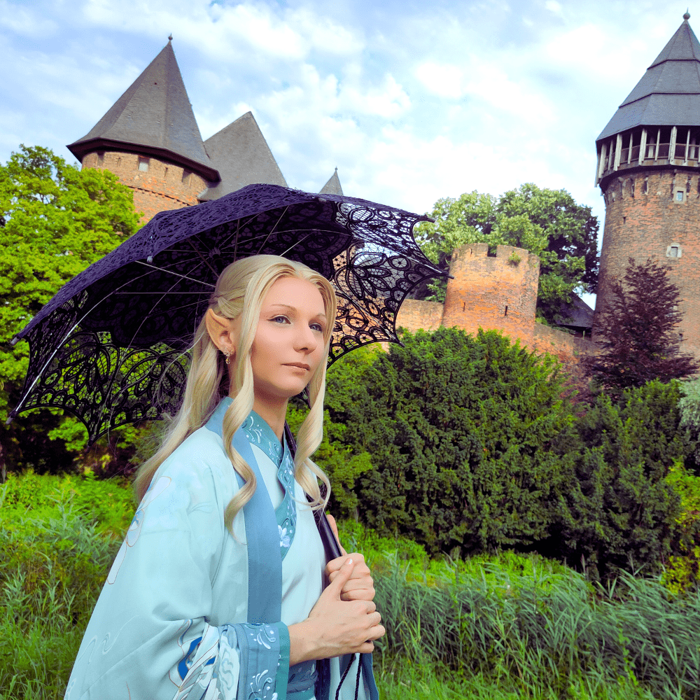 Frau in Elfenkostüm vor einer Burg.