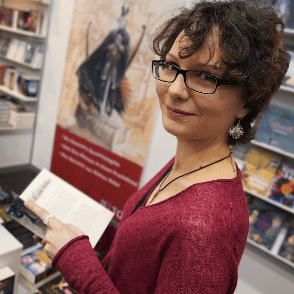 Autorin Aria Rauh hält ein Buch in der Hand.