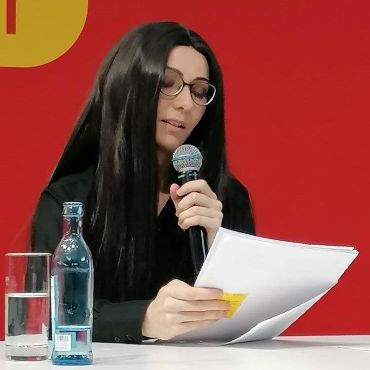 Frau mit langen, schwarzen Haaren und Brille liest auf der Leipziger Buchmesse.
