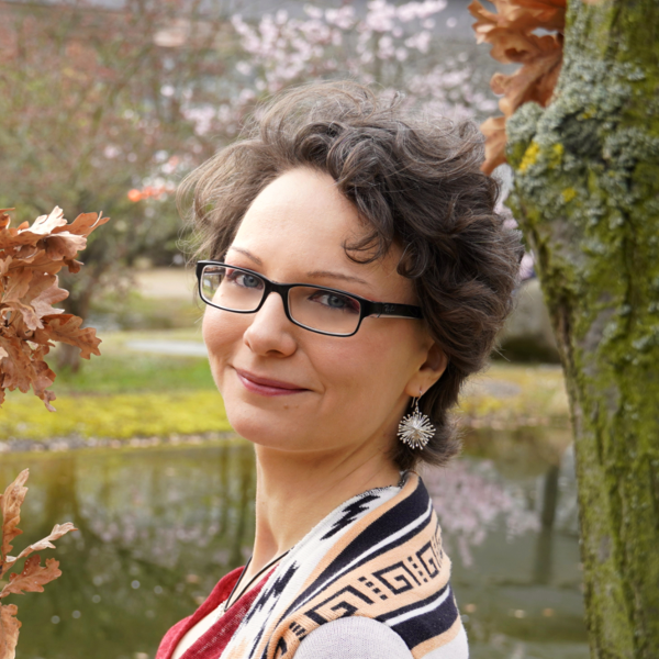 Portraitfoto der Autorin. Lächelnde Frau mit kurzen gelockten Haaren und Brille.